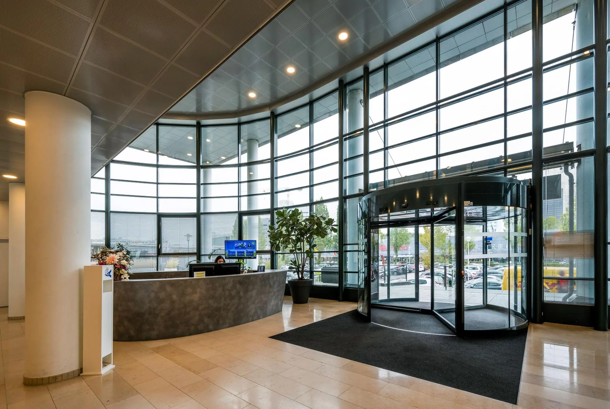 Moderne entreehal met een receptiebalie, glazen draaideur en hoge raampartijen aan de Watermanweg.