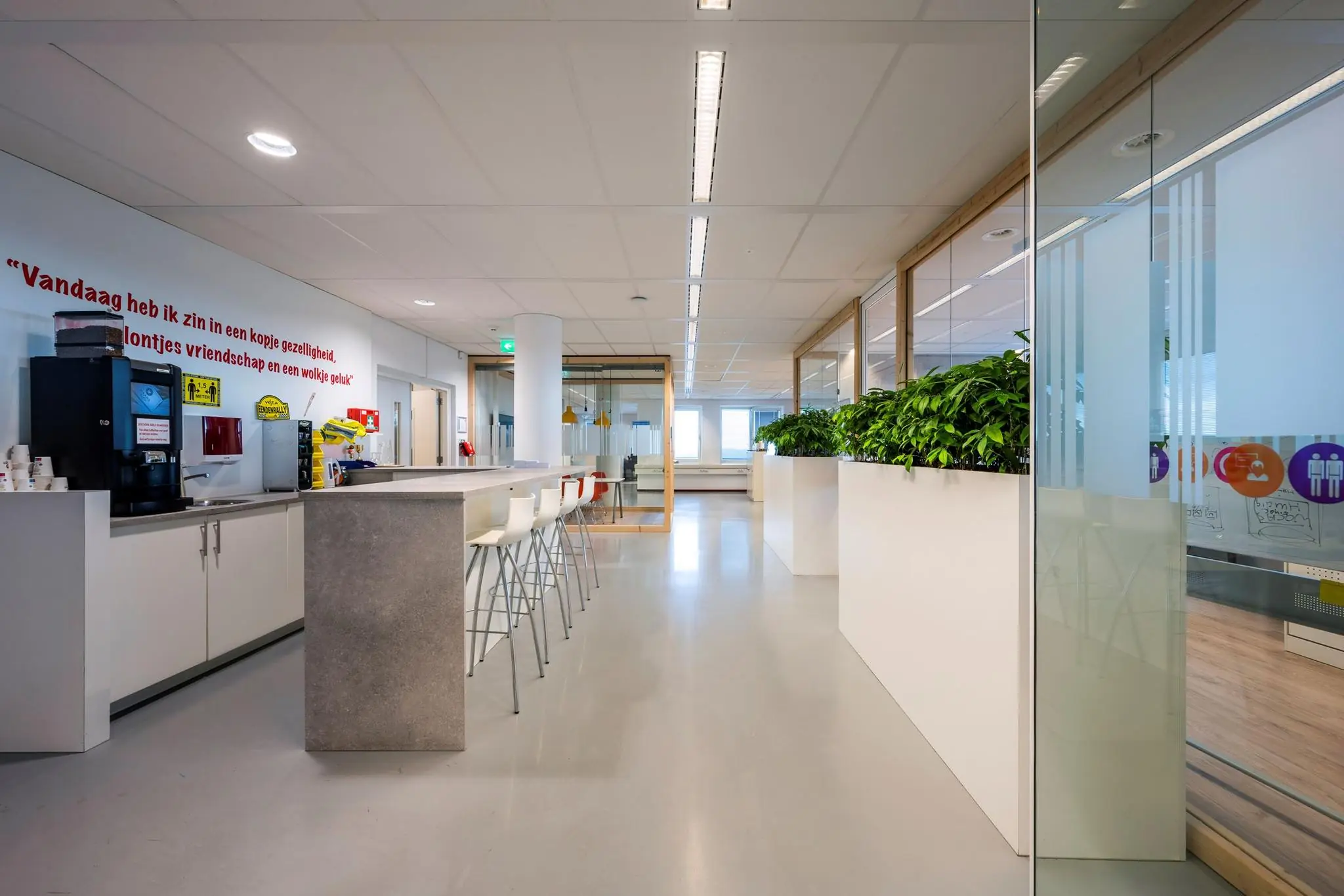 Moderne, lichte kantoorruimte aan de Watermanweg met een koffiehoek, hoge zitplekken en glazen vergaderruimtes.
