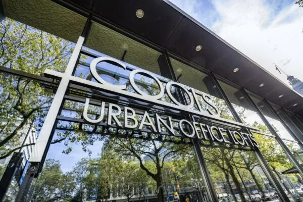 Glazen gevel van COOLS Urban Office Lofts aan de Coolsingel in Rotterdam met weerspiegeling van bomen en gebouwen.