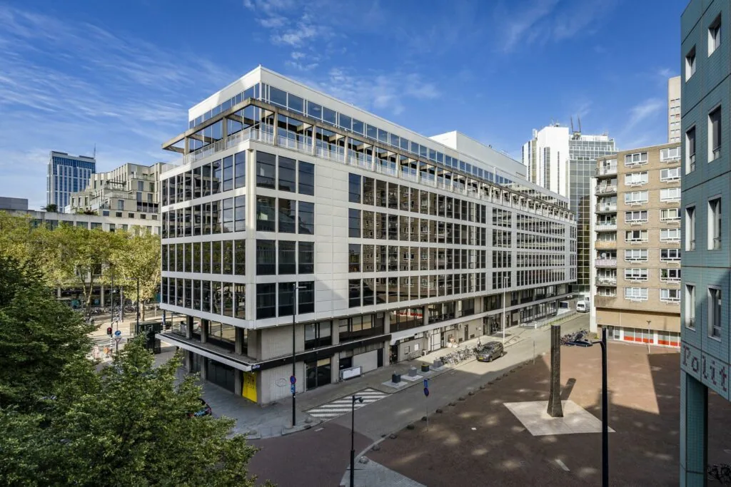 Modern kantoorgebouw aan de Coolsingel in Rotterdam met omliggende hoogbouw en een plein met kunstobject.