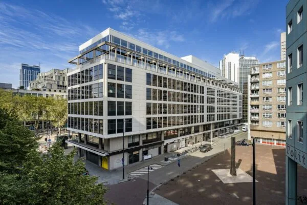 Modern kantoorgebouw aan de Coolsingel in Rotterdam met omliggende hoogbouw en een plein met kunstobject.