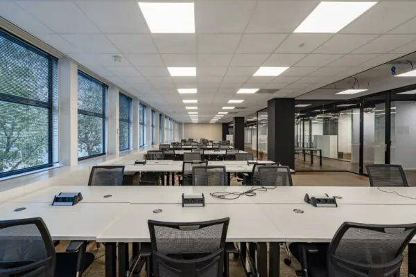 Moderne, open kantoorruimte aan de Coolsingel met rijen bureaus, bureaustoelen en grote ramen aan de linkerzijde.