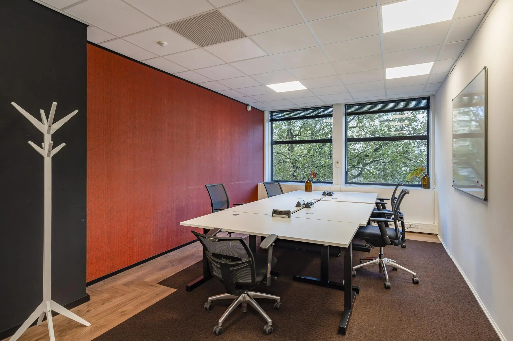 Vergaderruimte op de Coolsingel met moderne tafel, bureaustoelen en grote ramen met uitzicht op groen.