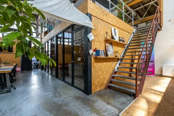 Industrieel ingerichte kantoorruimte aan de Eendrachtlaan met houten wanden, glazen kantoorunits en een stalen trap naar de bovenverdieping.