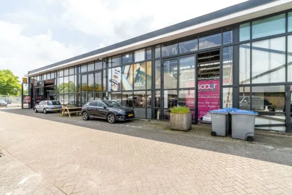 Bedrijfsgebouw aan de Eendrachtlaan met grote glazen gevel, geparkeerde auto's en zicht op het kantoor van Sooqr.