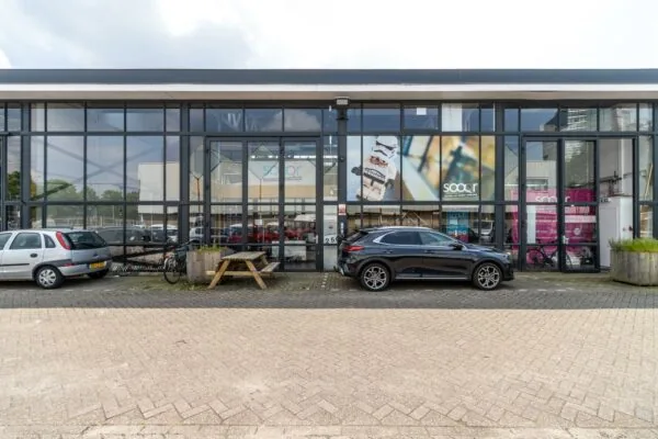 Vooraanzicht van een modern kantoorpand aan de Eendrachtlaan met geparkeerde auto's, fietsen en het logo van Sooqr.