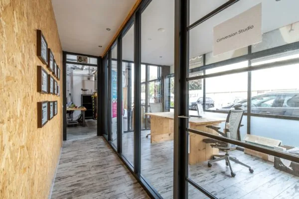 Moderne kantoorruimte aan de Eendrachtlaan met glazen wanden, houten meubels en een bord met de tekst "Conversion Studio".