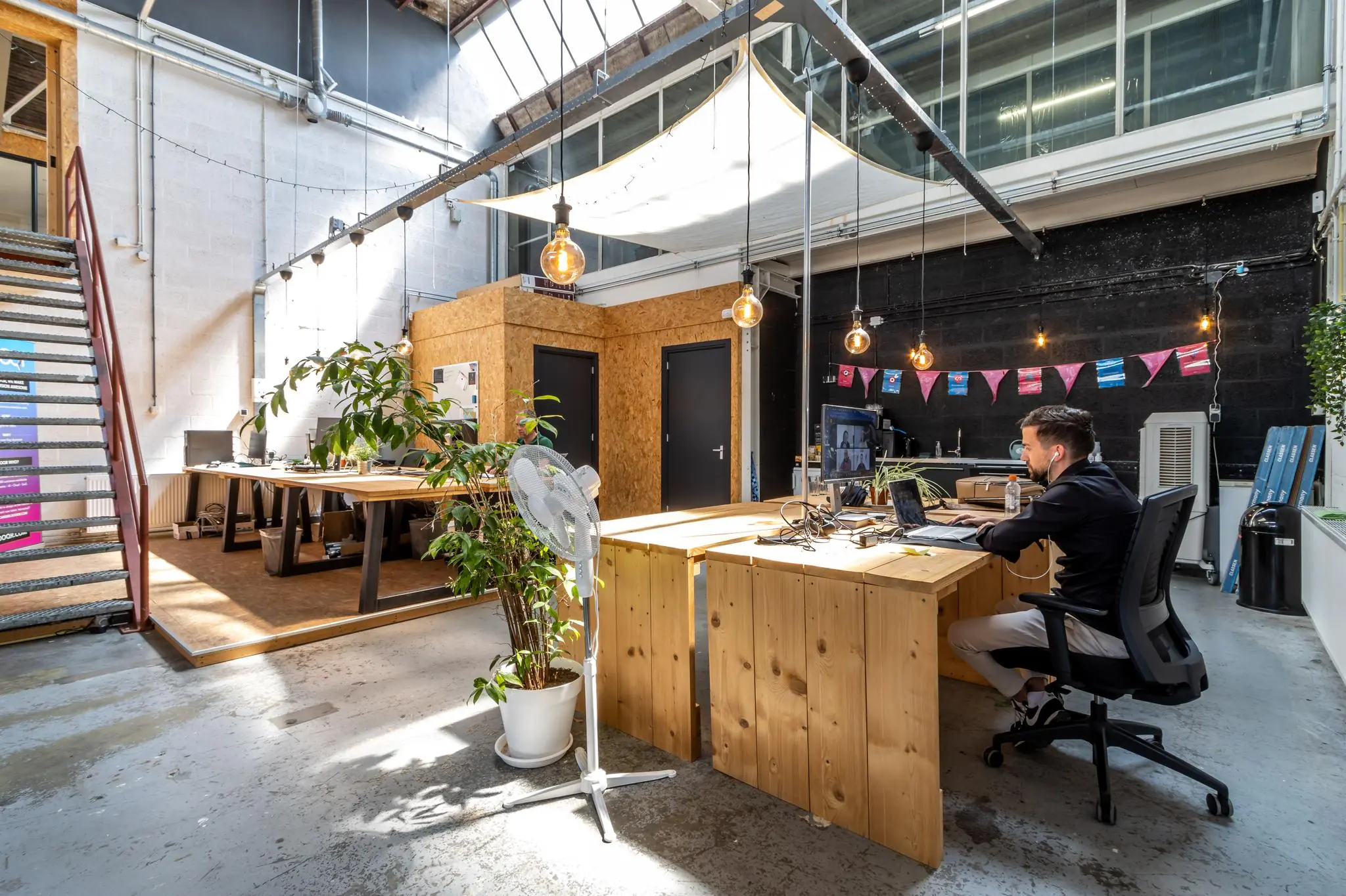 Modern kantoorinterieur aan de Eendrachtlaan met houten bureaus, industriële elementen en een man werkend achter een laptop.