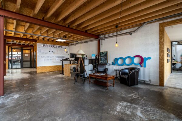 Moderne kantoorruimte aan de Eendrachtlaan met een open zithoek, 'Product Wall' en Sooqr-logo op de muur.
