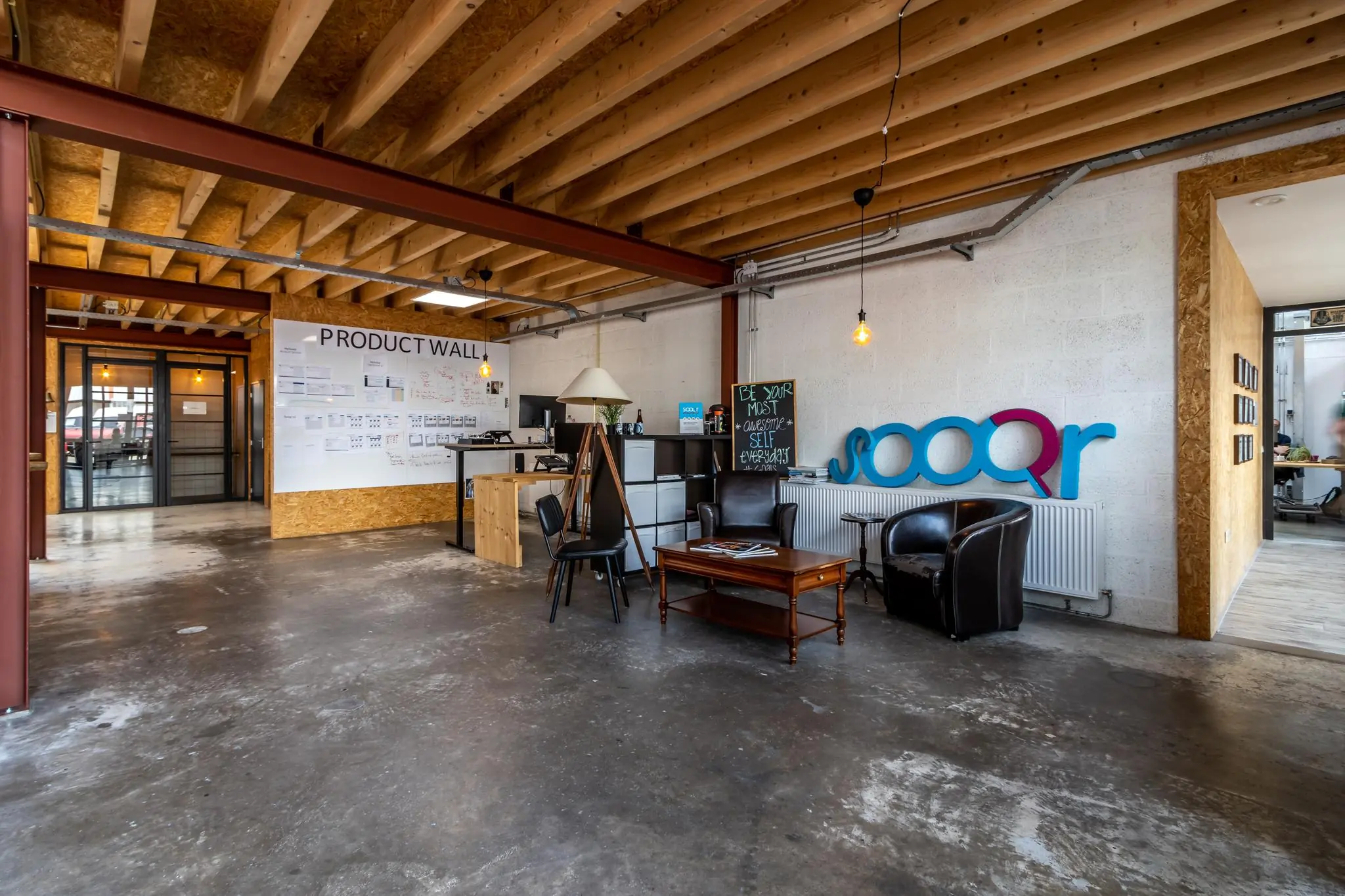 Moderne kantoorruimte aan de Eendrachtlaan met een open zithoek, 'Product Wall' en Sooqr-logo op de muur.