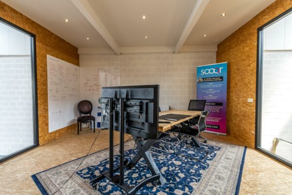 Moderne vergaderruimte aan de Eendrachtlaan met houten wanden, groot scherm, whiteboards en een Sooqr-promotiebanner.