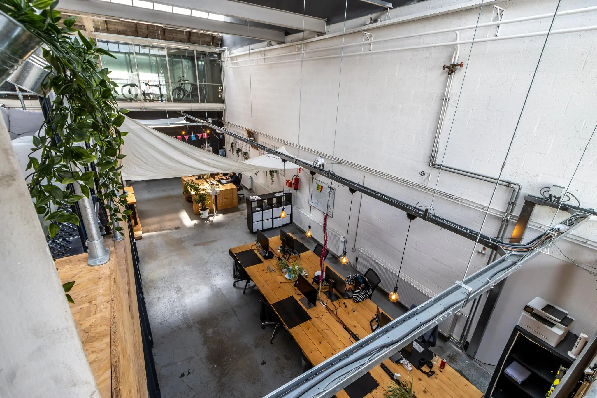 Modern industrieel kantoorinterieur aan de Eendrachtlaan met open werkplekken, houten bureaus en hangende verlichting.