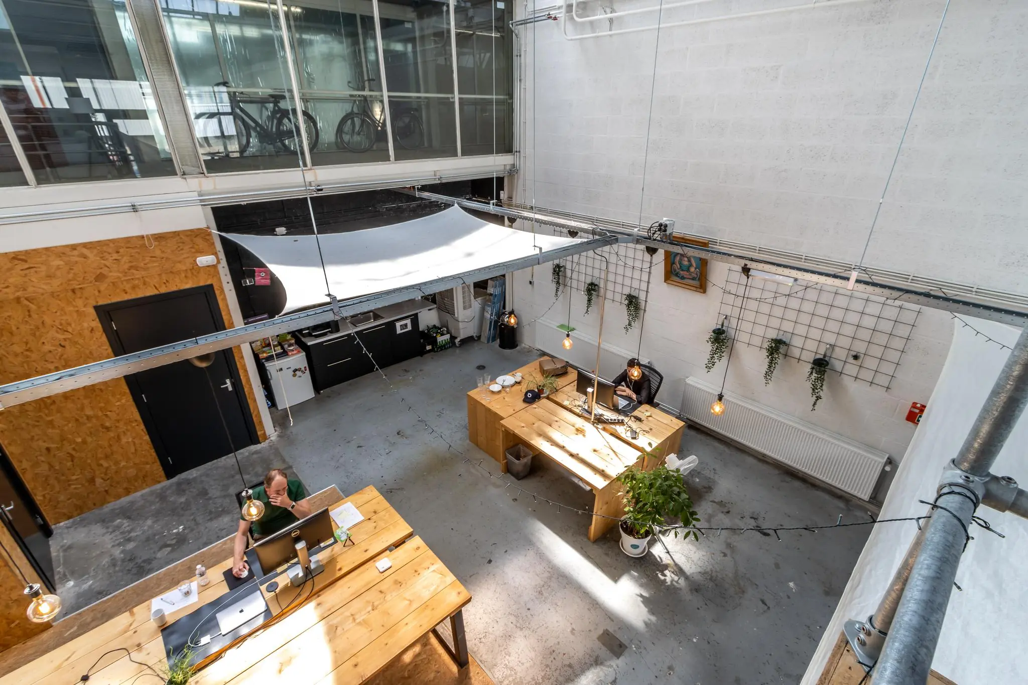 Licht en modern kantoorpand aan de Eendrachtlaan met houten bureaus, hangplanten en industrieel interieur.