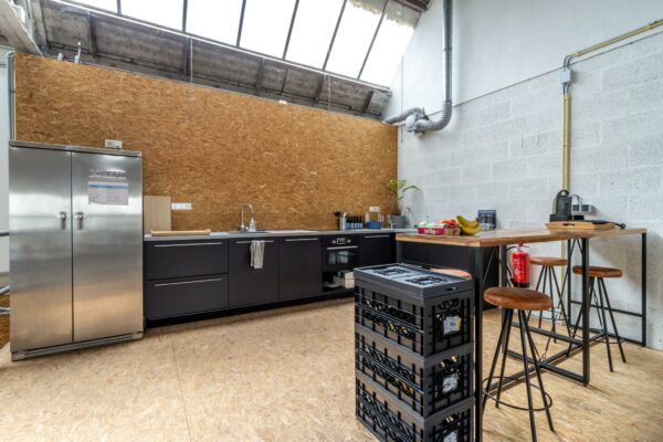 Industrieel ingerichte keuken aan de Eendrachtlaan met zwarte kasten, rvs-koelkast, houten bar en hoge krukken.