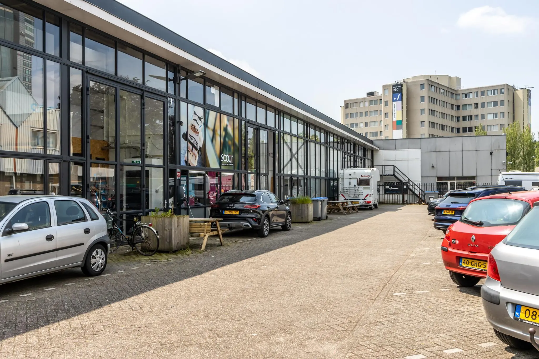 Bedrijfsgebouw aan de Eendrachtlaan met geparkeerde auto's en een camper op de parkeerplaats.