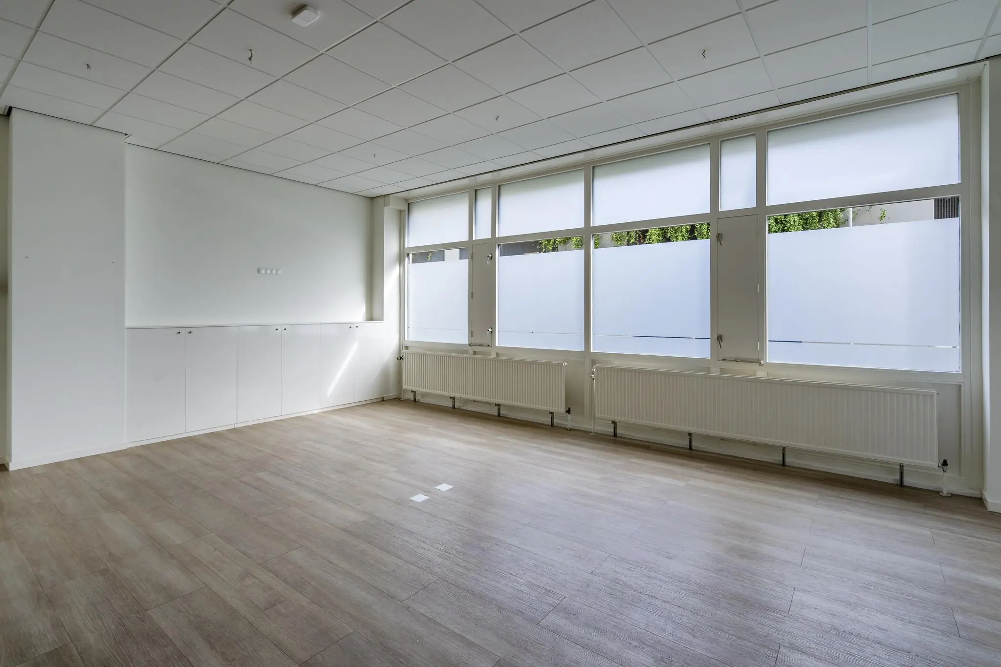 Lichte, lege kantoorruimte aan de Coolsingel met grote ramen en een houten vloer.