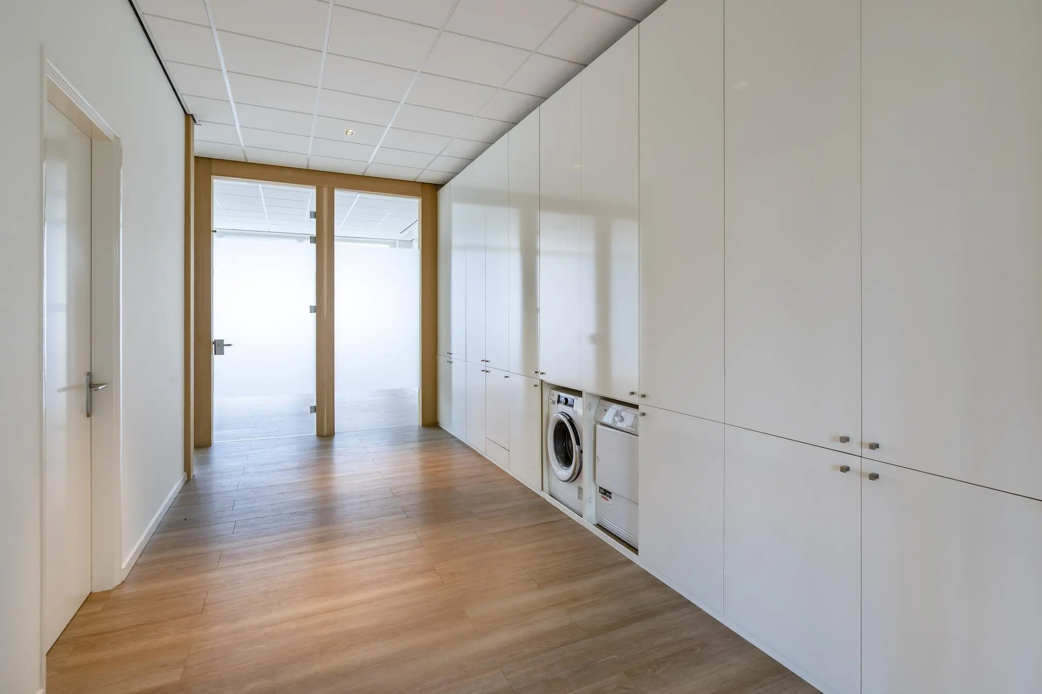 Moderne wasruimte met inbouwkasten, een wasmachine en een droger aan de Coolsingel.