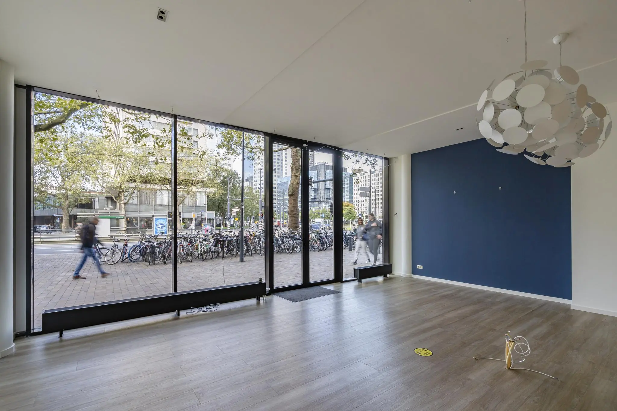 Leegstaand winkel- of kantoorpand met grote glazen pui aan de Coolsingel in Rotterdam, met uitzicht op voorbijgangers en fietsenrekken.