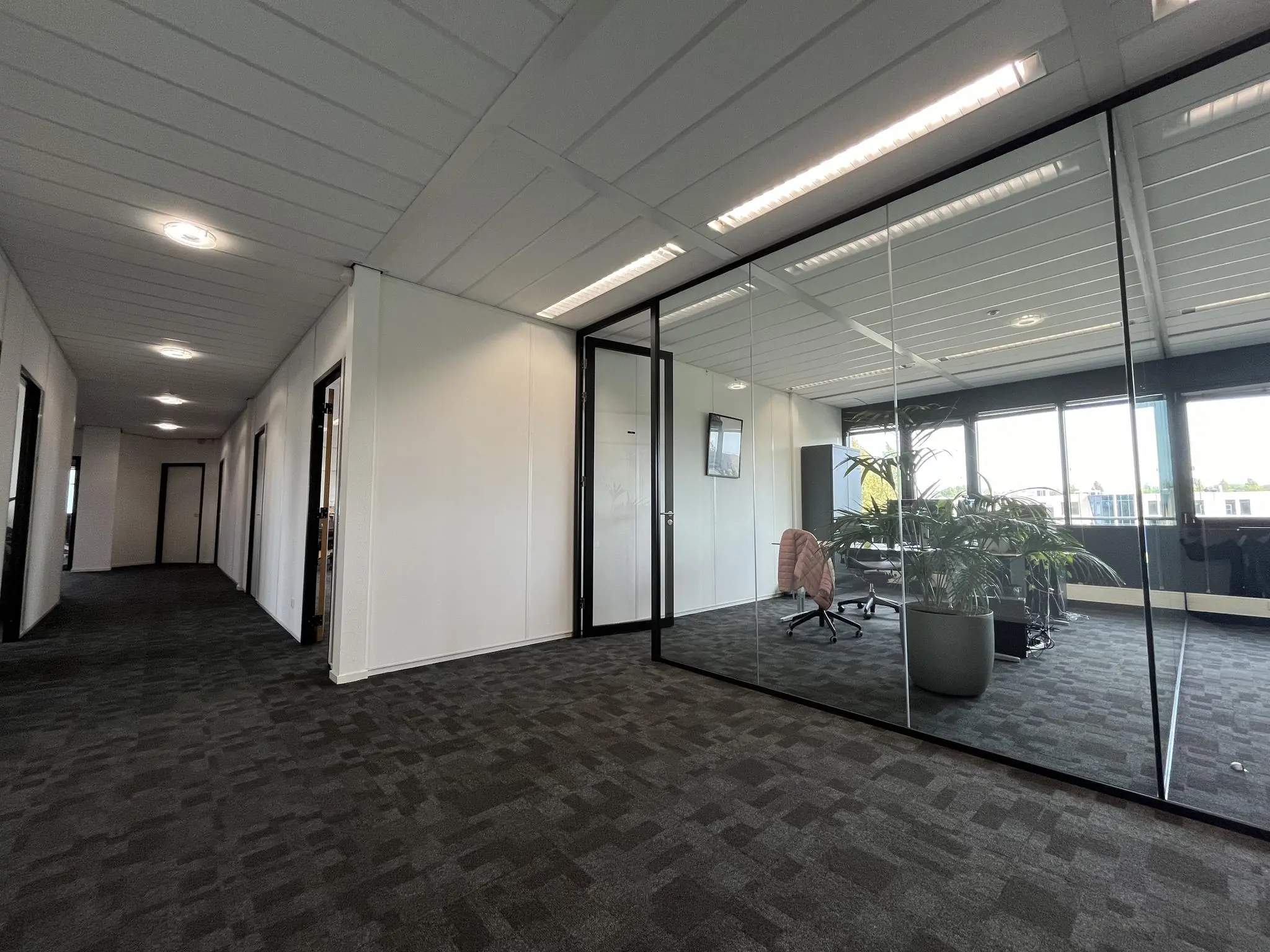 Moderne kantoorruimte aan de Wattbaan met glazen vergaderruimte en uitzicht op buiten.