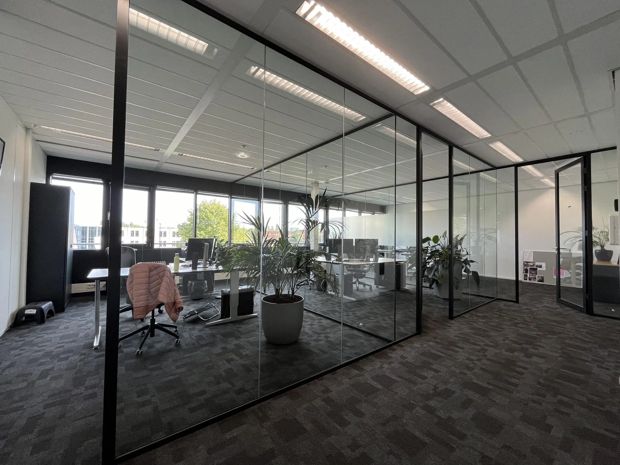 Moderne kantoorruimte aan de Wattbaan met glazen wanden, bureaus en kantoorplanten.