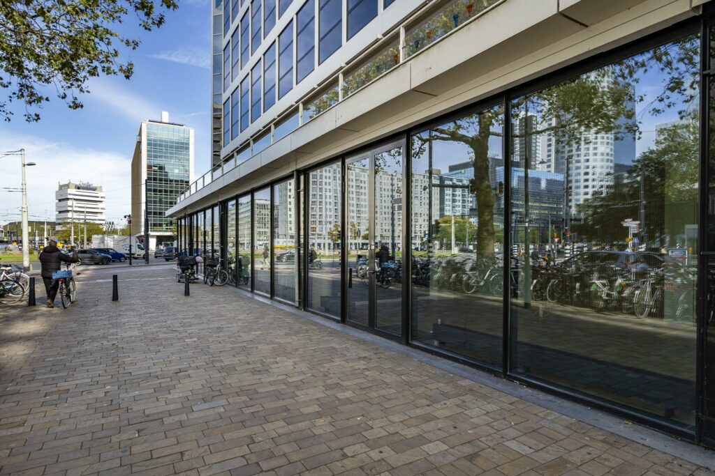 Moderne kantoorgebouwen en fietsparkeerplaatsen langs de Coolsingel in Rotterdam op een zonnige dag.