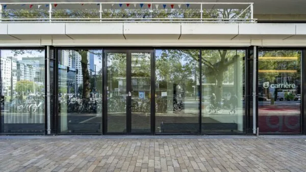 Glazen gevel van een kantoor aan de Coolsingel in Rotterdam met het logo van uitzendbureau Carrière zichtbaar op het rechterraam.