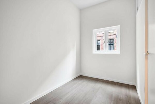 Lichte, lege kamer met witgestuukte muren en een raam met uitzicht op de Westerstraat.