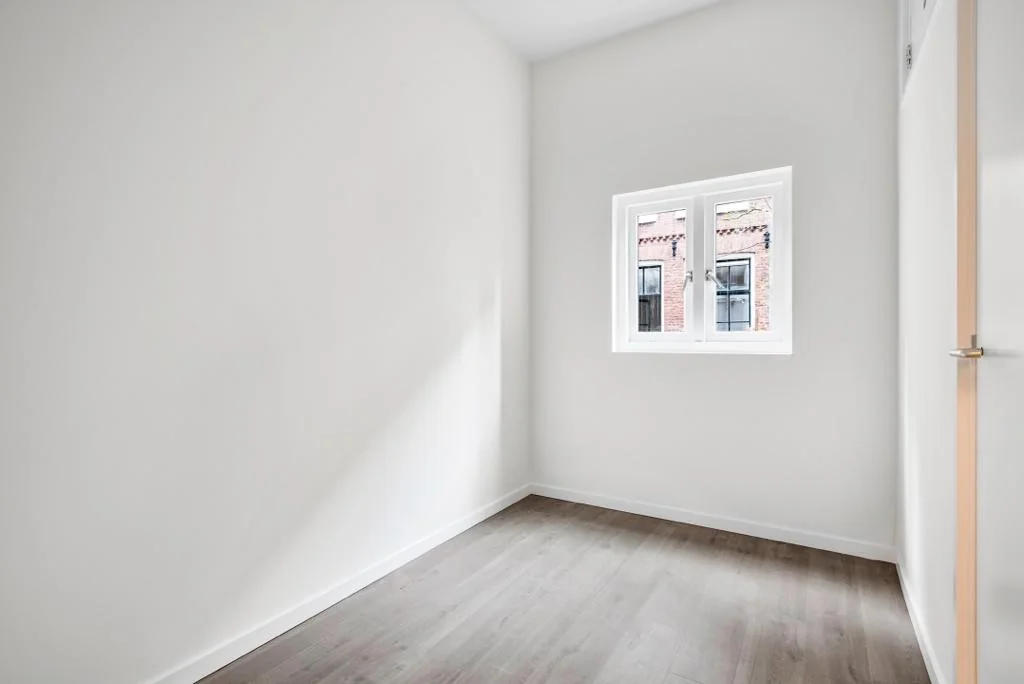 Lichte, lege kamer met witgestuukte muren en een raam met uitzicht op de Westerstraat.