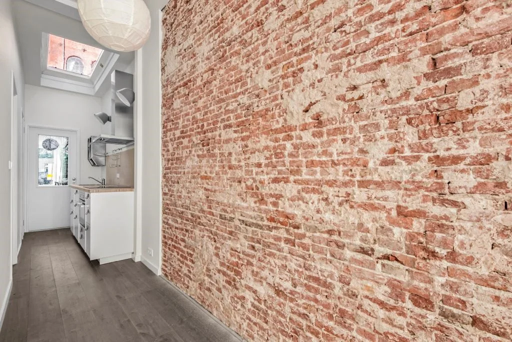 Smalle keuken met een zichtbare bakstenen muur in een appartement aan de Westerstraat.