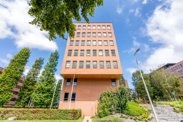 Kantoorgebouw aan de Hullenbergweg met rode bakstenen gevel, omgeven door groen en trappen.