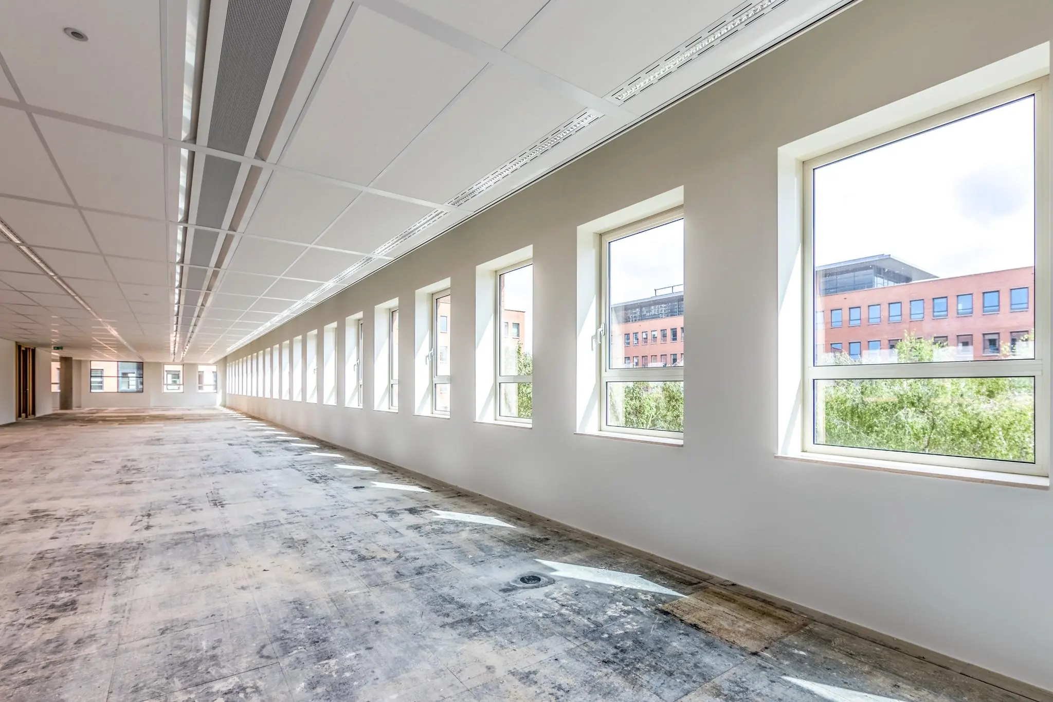 Lichte, lege kantoorruimte aan de Hullenbergweg met grote ramen en systeemplafond.