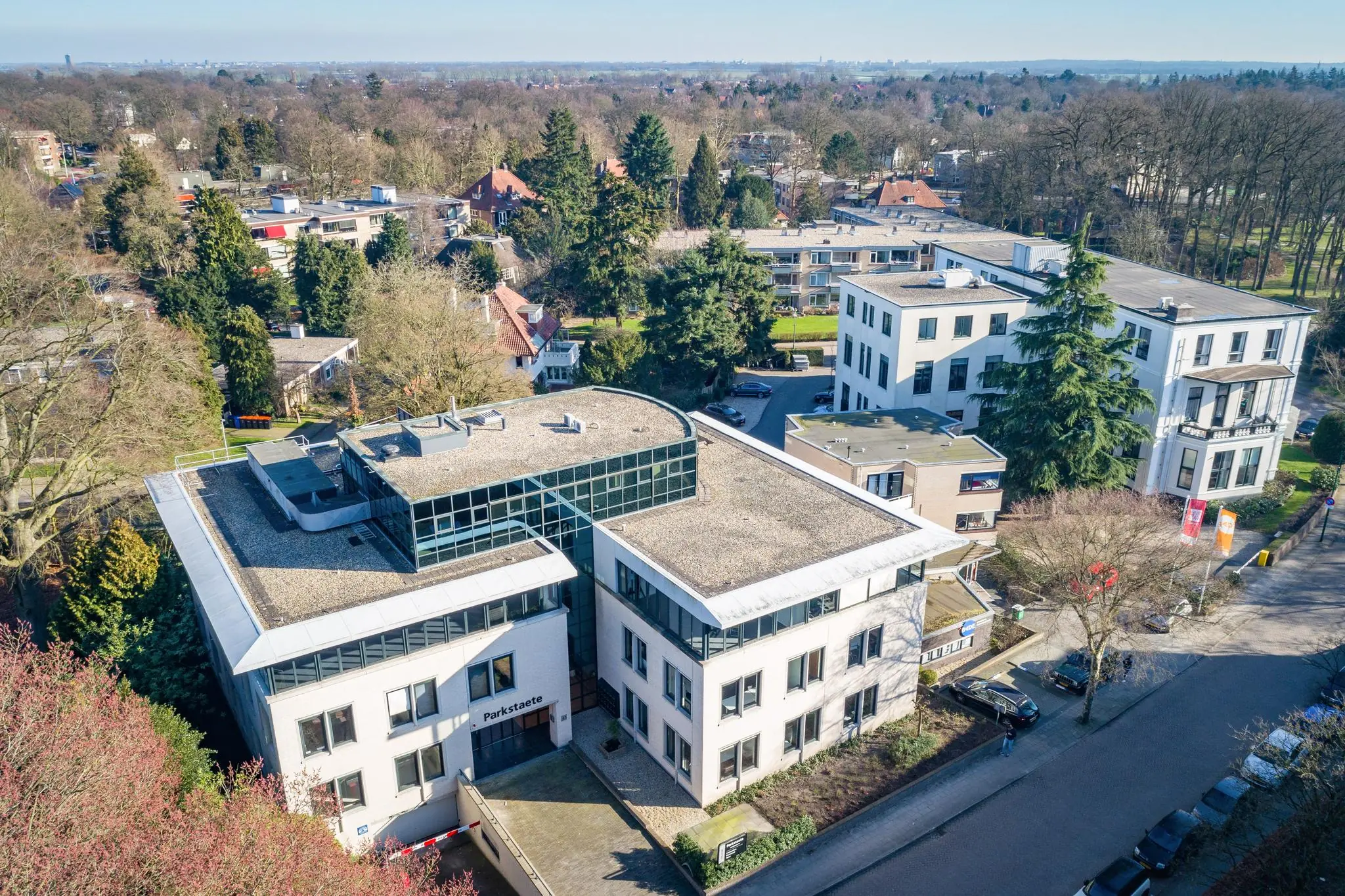 Luchtfoto van het kantoorgebouw Parkstaete aan de Amalialaan, omringd door bomen en andere gebouwen.
