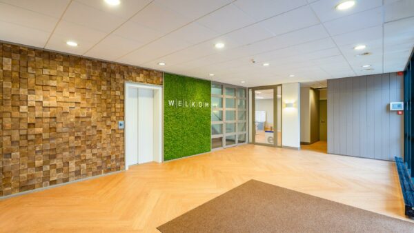 Moderne en sfeervolle entree van een kantoorpand aan de Amaliastraat met groenemuur en houten accenten.
