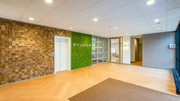 Moderne en sfeervolle entree van een kantoorpand aan de Amaliastraat met groenemuur en houten accenten.