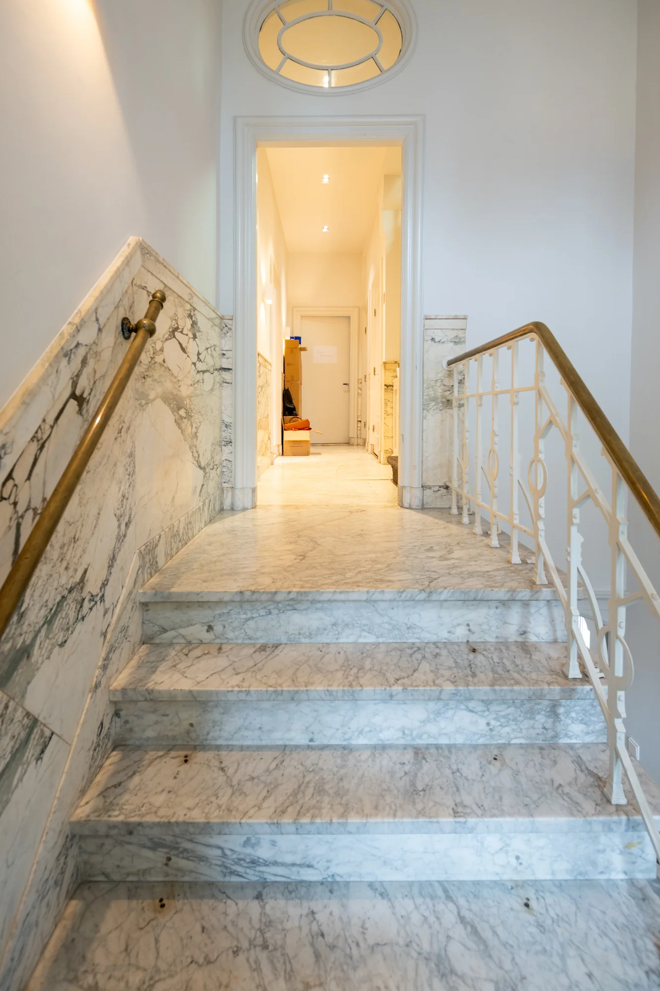 Marmeren trap in een klassiek trappenhuis aan de Hobbemastraat met zicht op een verlichte gang.