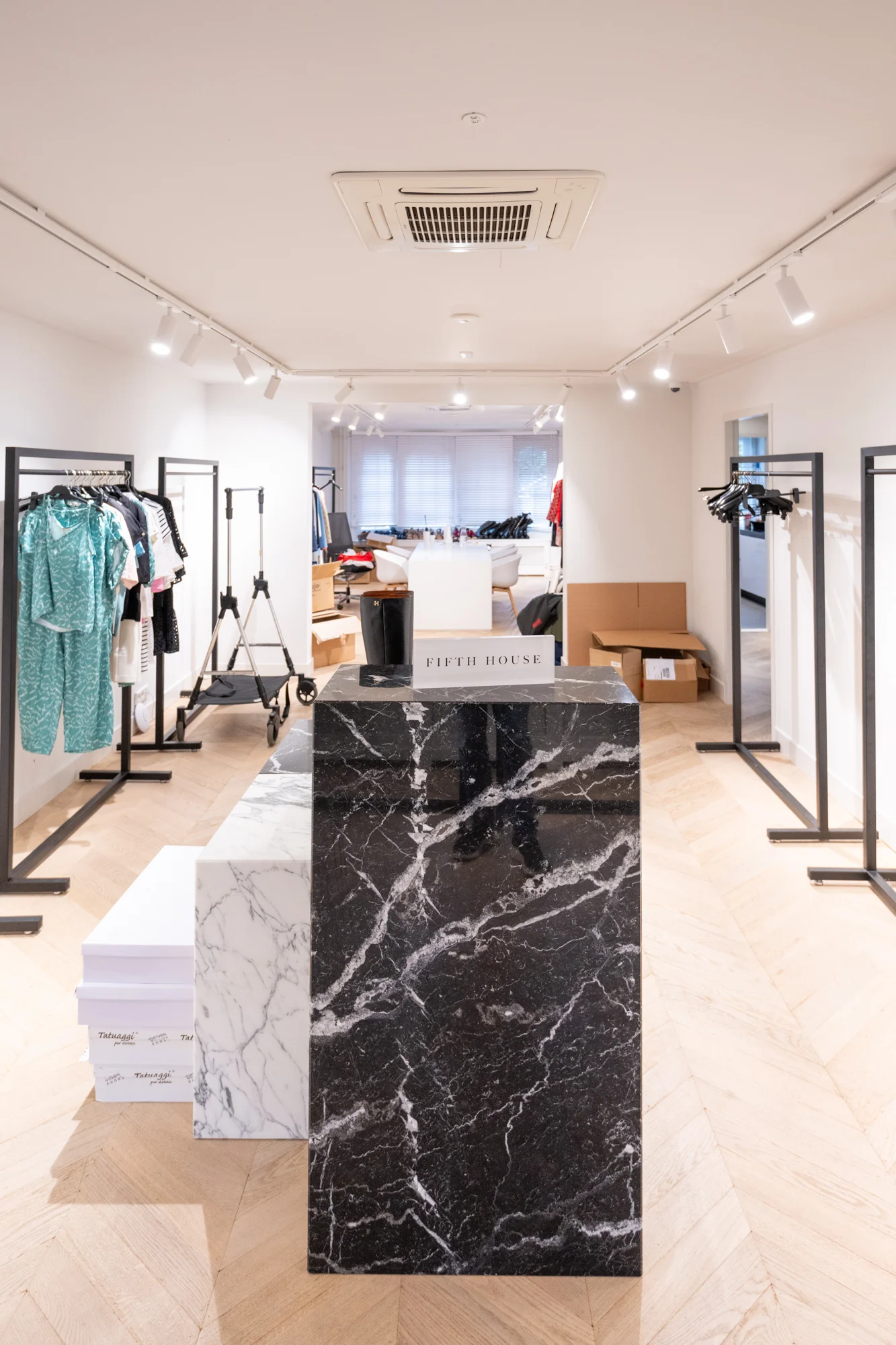 Moderne showroom van het kledingmerk Fifth House aan de Hobbemastraat met kledingrekken, marmeren balie en verpakkingsdozen.