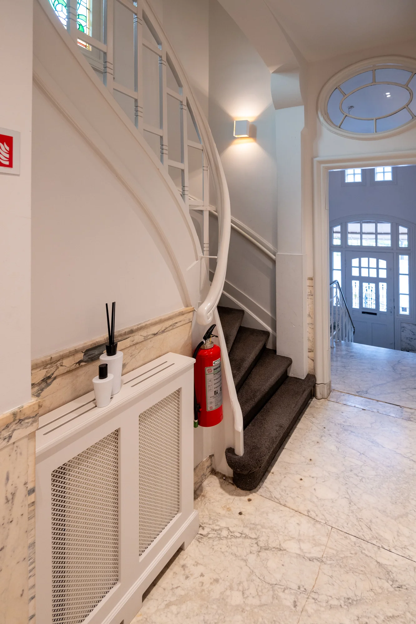 Marmeren hal met trap, brandblusser en sierlijke details in een gebouw aan de Hobbemastraat.