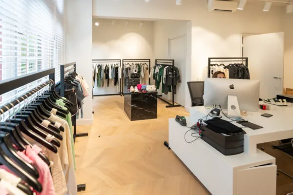 Moderne kledingwinkel aan de Hobbemastraat met neatly opgehangen kledingrekken, een centrale display en een balie met computer.