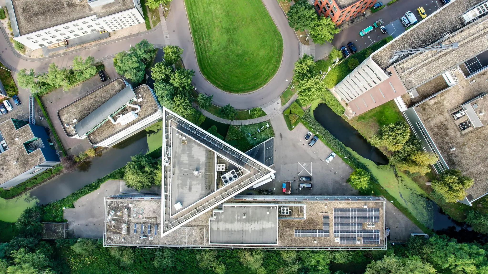 Luchtfoto van het Delftechpark met een driehoekig gebouw omringd door kantoren, groenstroken en water.