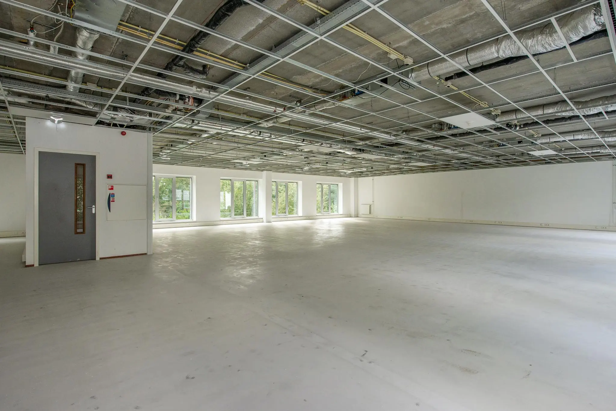 Leeg kantoorpand in Delftechpark met open systeemplafond en grote ramen.