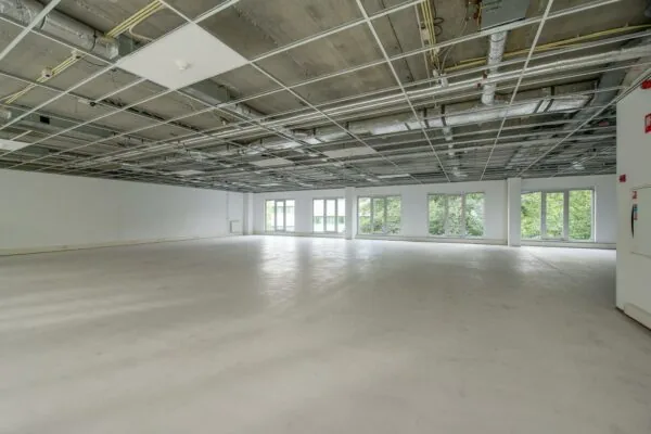 Leeg, licht en ruim kantoorinterieur in Delftechpark met onafgewerkt plafond en grote ramen.