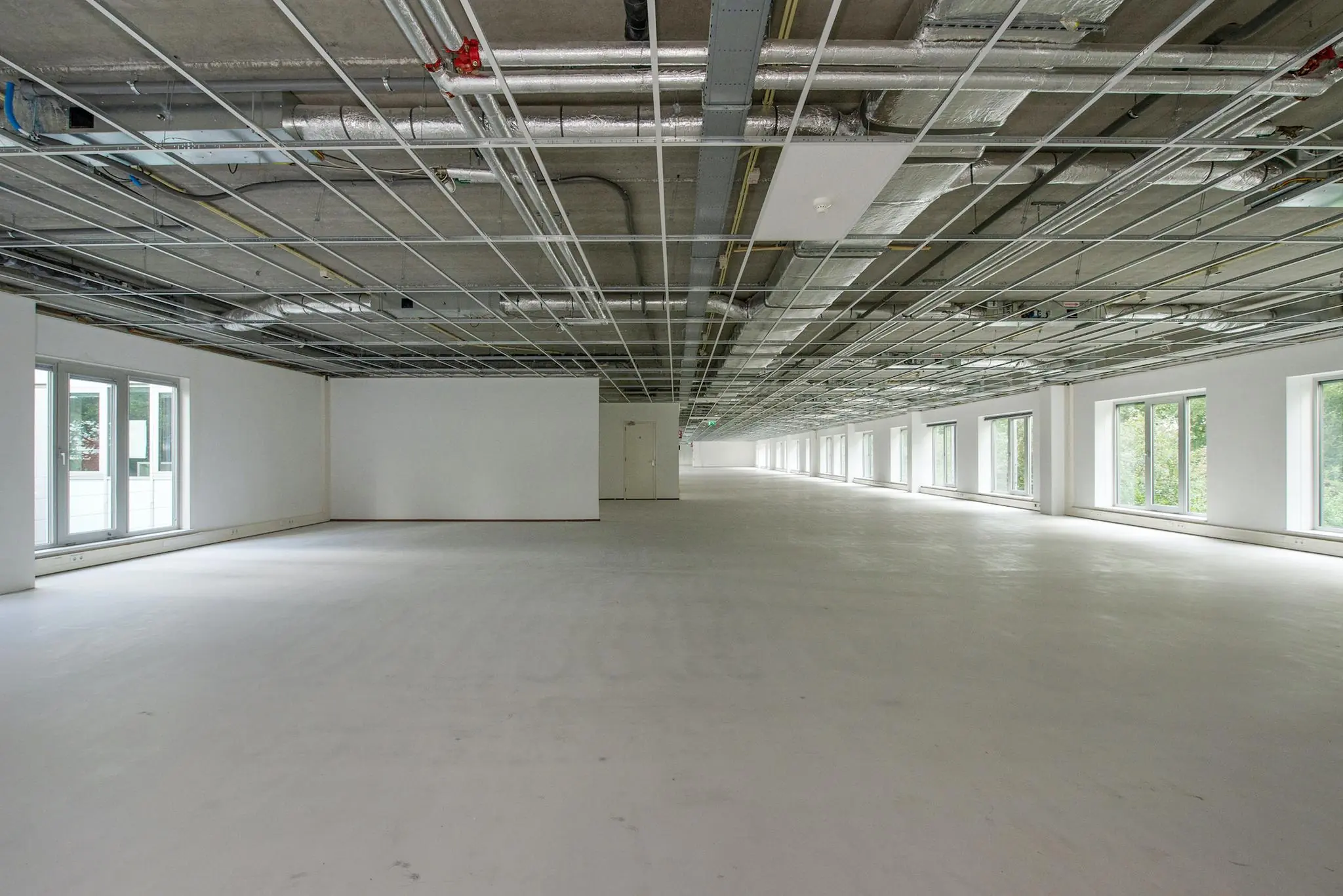 Leeg kantoorpand in Delftechpark met zichtbare plafonds en grote ramen aan één zijde.