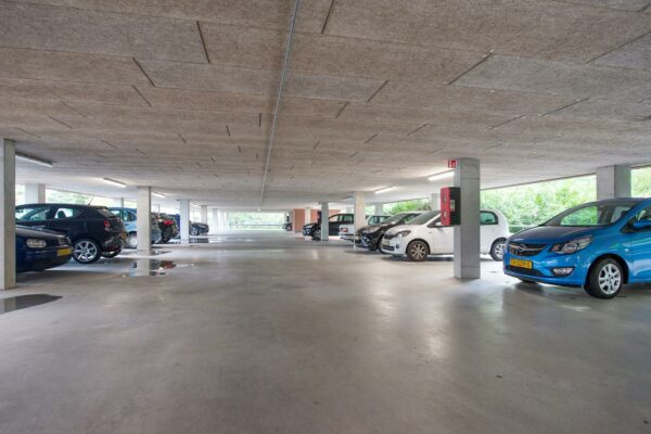 Overdekte parkeergarage op Delftechpark met meerdere geparkeerde auto's en betonnen kolommen.