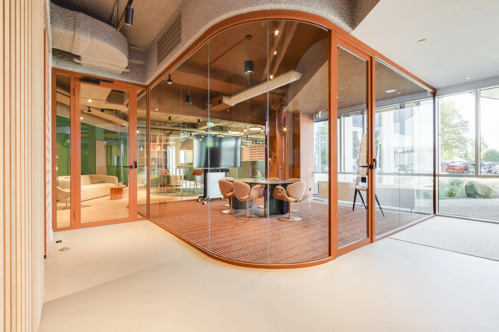 Glazen vergaderruimte met oranje accenten in het Sloterdijk-Collaboration kantoor met uitzicht naar buiten.