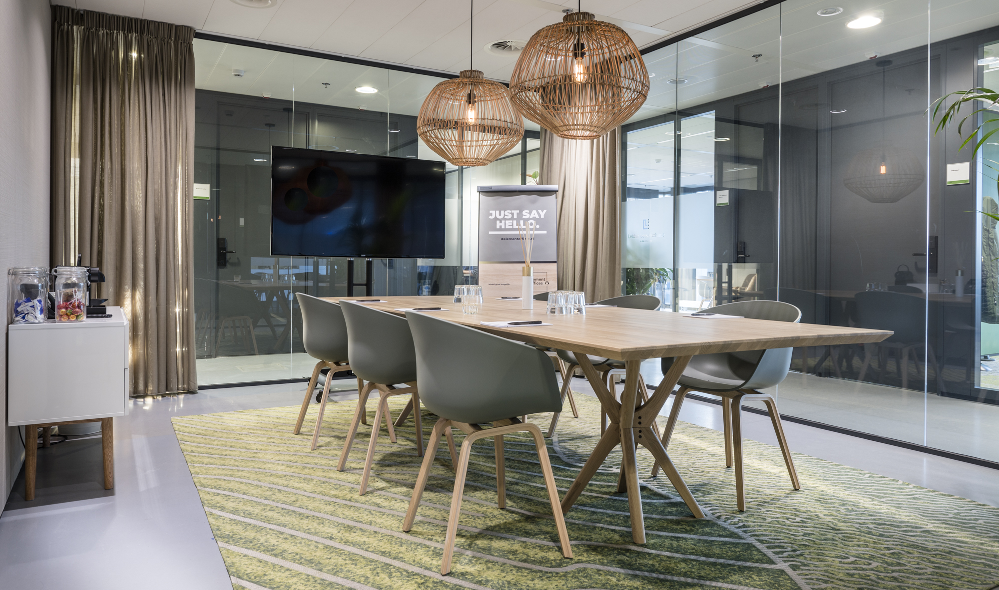 Een moderne vergaderruimte met een houten tafel, designstoelen, glazen wanden en decoratieve hanglampen.