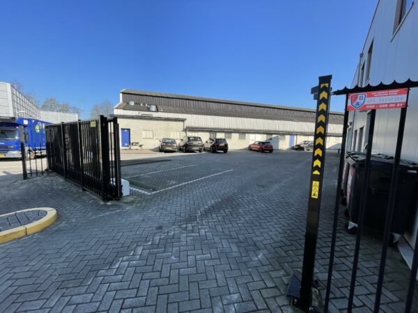 Bedrijfsterrein aan de Kwekerijweg met parkeervakken, beveiligingshek en borden van JBA Security.