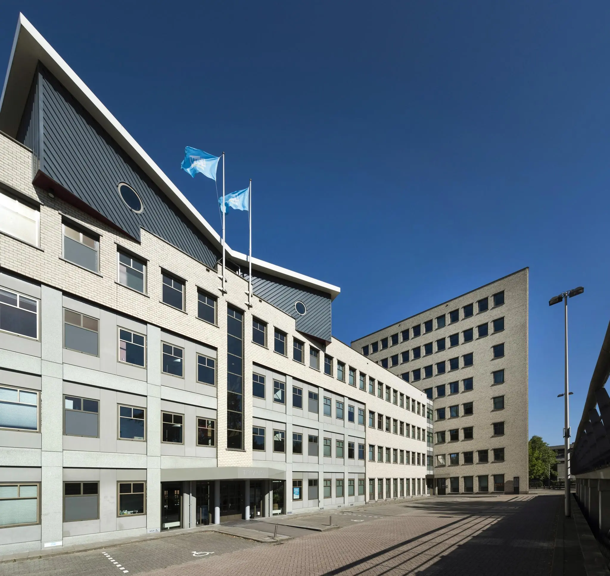 Kantoorgebouw aan de Derkinderenstraat in Amsterdam met twee vlaggen op het dak en een ruime binnenplaats.