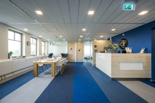 Moderne kantoorruimte aan de Derkinderenstraat met een ontvangstbalie, vergadertafel en blauwe accenten.