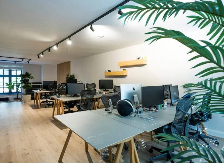 Modern kantoorinterieur aan de Sarphatistraat met meerdere bureaus, computerschermen en ergonomische stoelen.