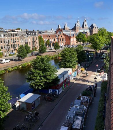Uitzicht op de Ruysdaelkade in Amsterdam met het Rijksmuseum op de achtergrond en een gracht langs de straat.